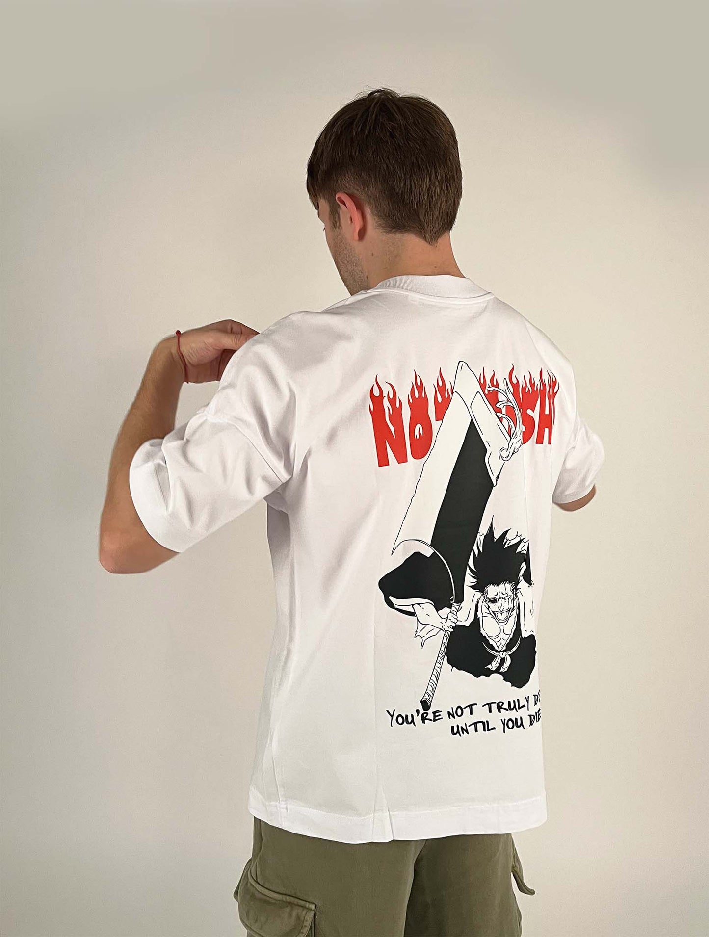 An oversized tshirt inspired by Zaraki Kenpachi from Bleach. Anime Pump Cover for the gym with Nozarashi text at top and Zaraki Kenpachi from Bleach. Text at bottom "You're not truly defeated until you die". Male model 3/4 design