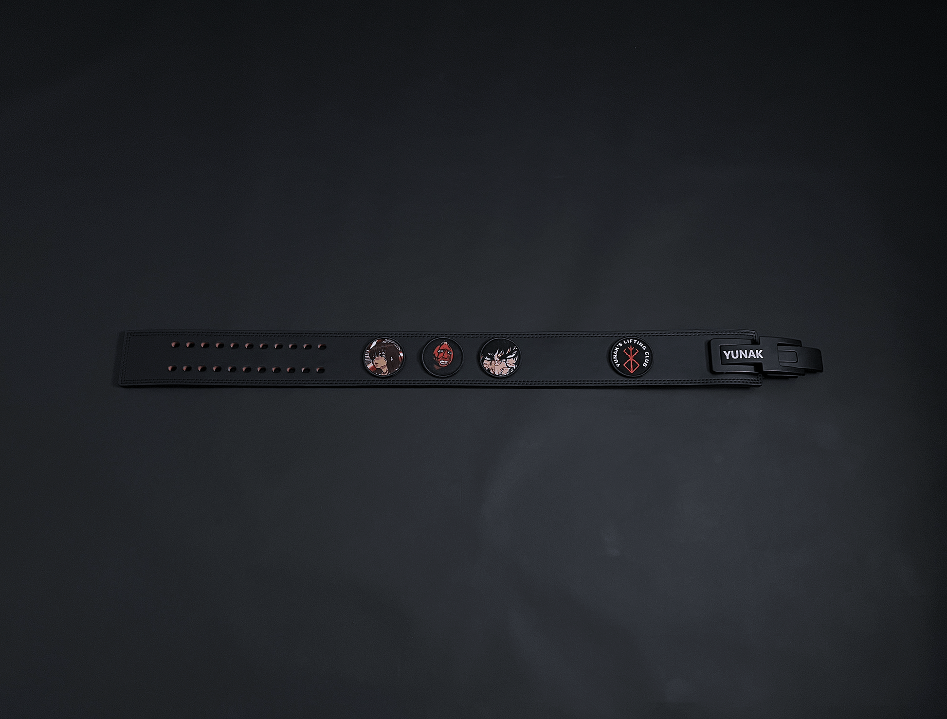 An anime powerlifting belt, 13mm thick and 4 inch wide. Featuring 4 embroidery patches inspired by Berserk. First patch is Casca, second is behelit, third is featuring Guts and the fourth is a Yunak's Lifting Club patch. The photo is top down view of the belt.