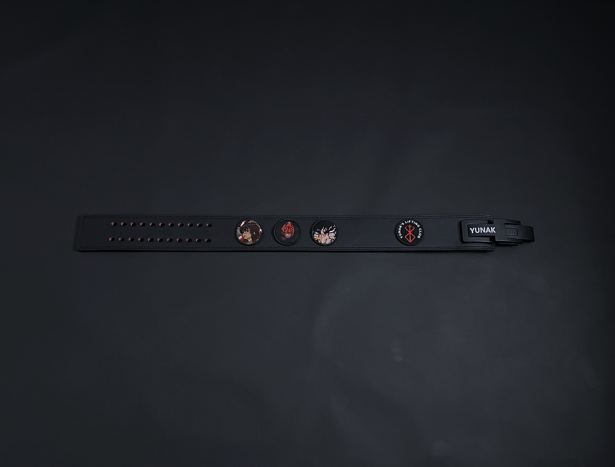 An anime powerlifting belt, 13mm thick and 4 inch wide. Featuring 4 embroidery patches inspired by Berserk. First patch is Casca, second is behelit, third is featuring Guts and the fourth is a Yunak's Lifting Club patch. The photo is top down view of the belt.