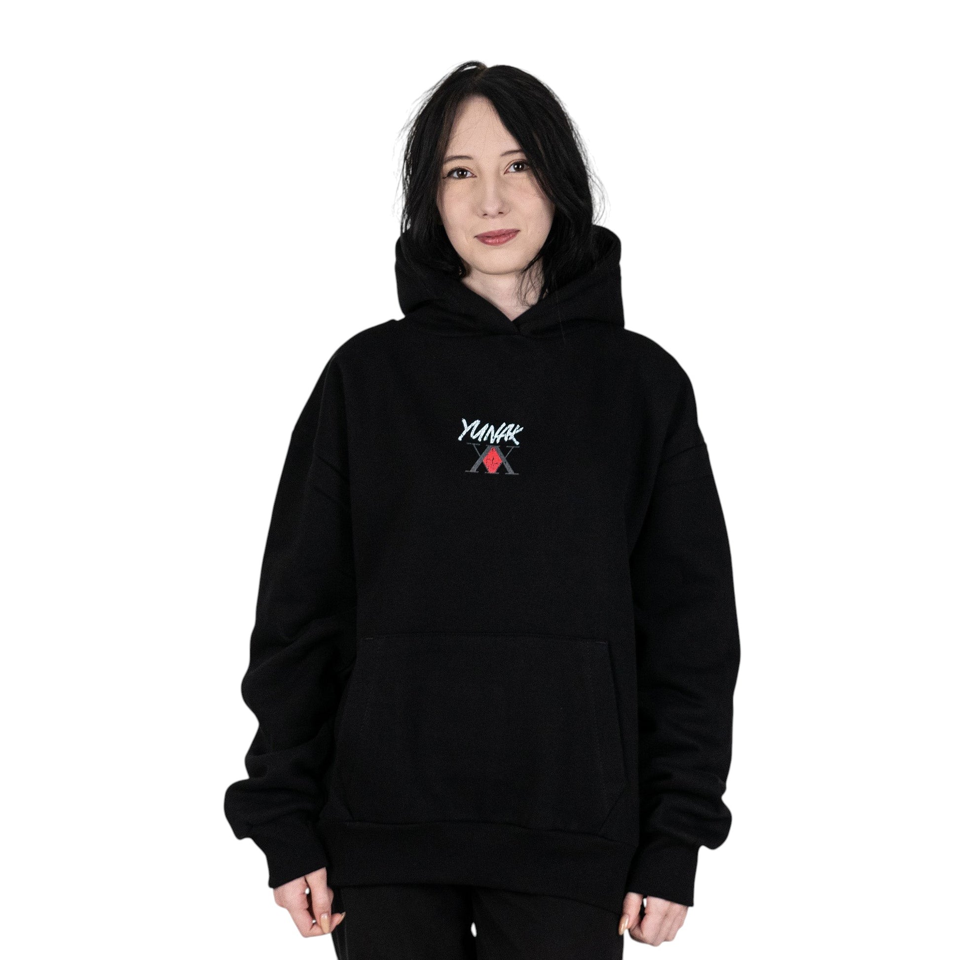 Person wearing a black hoodie with Yunak x HunterxHunter graphic on the front, standing against a white background