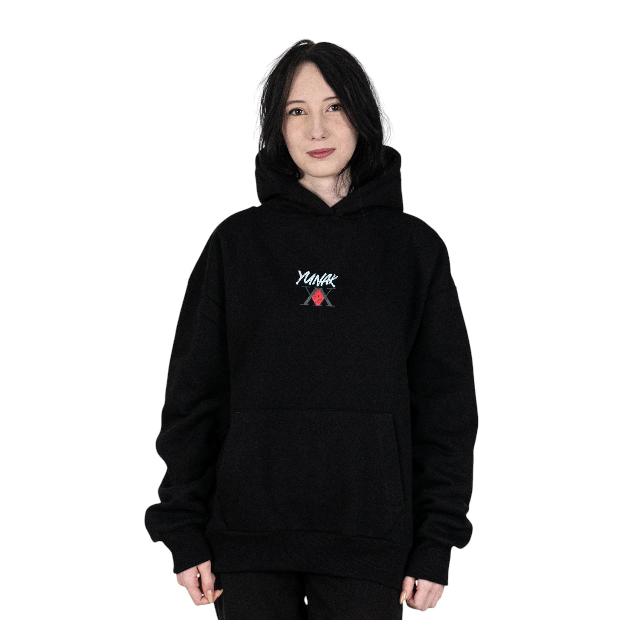 Person wearing a black hoodie with Yunak x HunterxHunter graphic on the front, standing against a white background