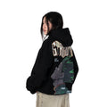 Person wearing a black hoodie with graphic design of Gon from HunterxHunter on the back, standing against a white background