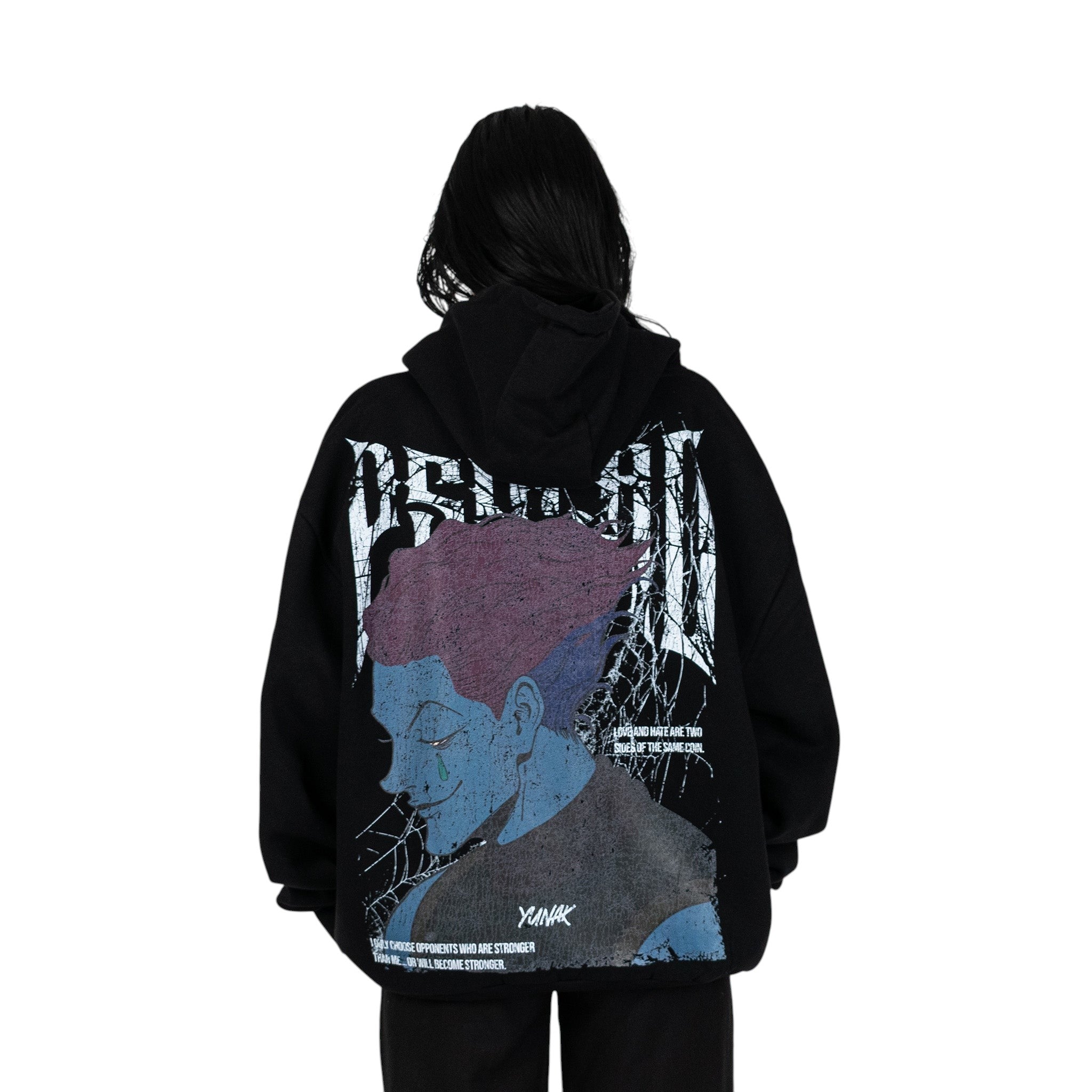 Person wearing a black hoodie with graphic design of Hisoka from HunterxHunter on the back, standing against a white background