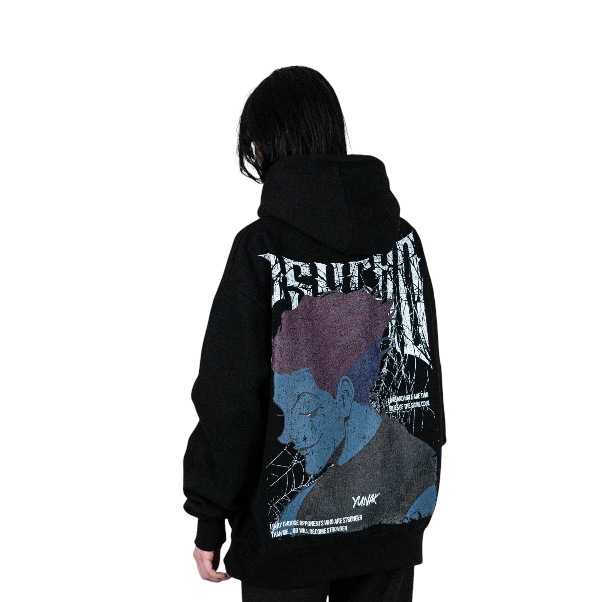 Person wearing a black hoodie with graphic design of Hisoka from HunterxHunter on the back, standing against a white background