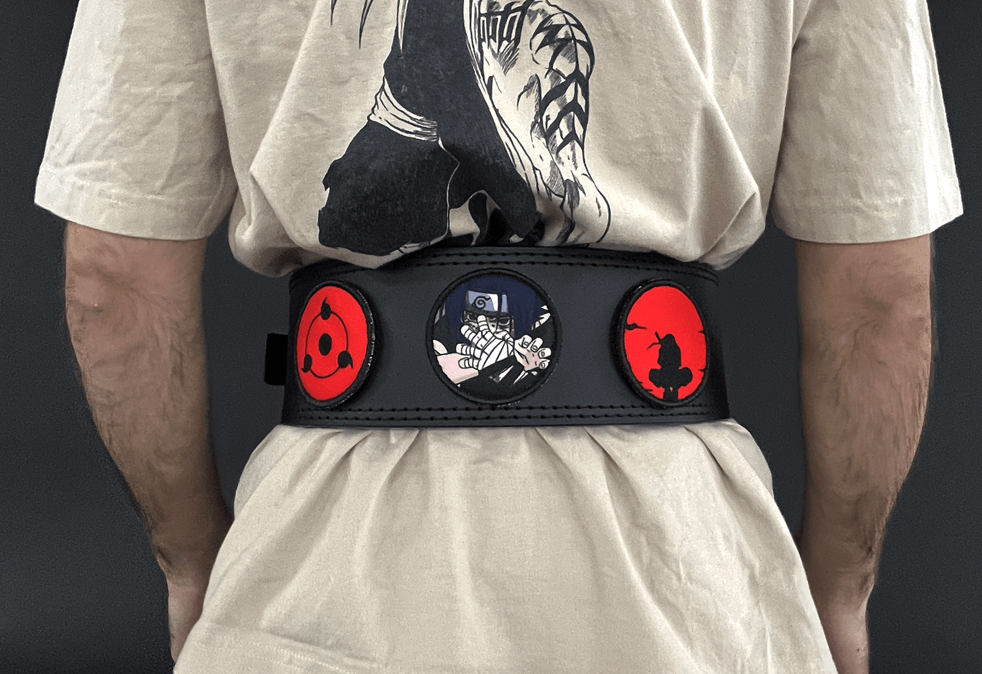 An anime powerlifting belt, 13mm thick and 4 inch wide being worn by a male. Featuring 4 embroidery patches inspired by the Akatsuki clan. First patch is Itachi bright red background, second is Sasuke, third is featuring the Sharingan. The photo is back view of the belt.