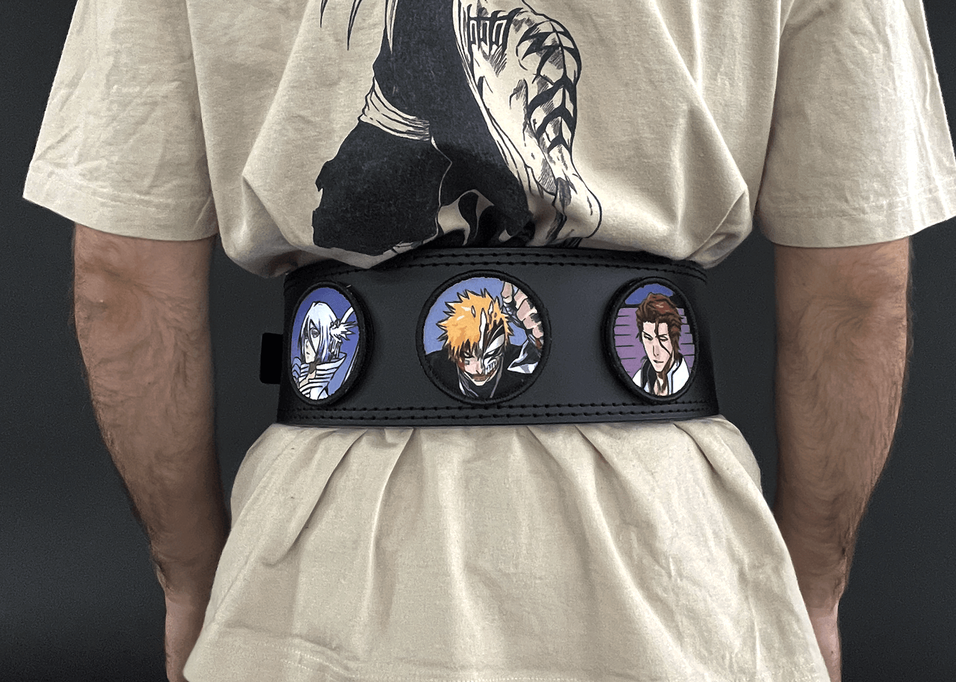 An anime powerlifting belt, 13mm thick and 4 inch wide being worn by a male. Featuring 4 embroidery patches inspired by Bleach. First patch is Rukia, second is Ichigo, third is featuring Aizen. The photo is back view of the belt.