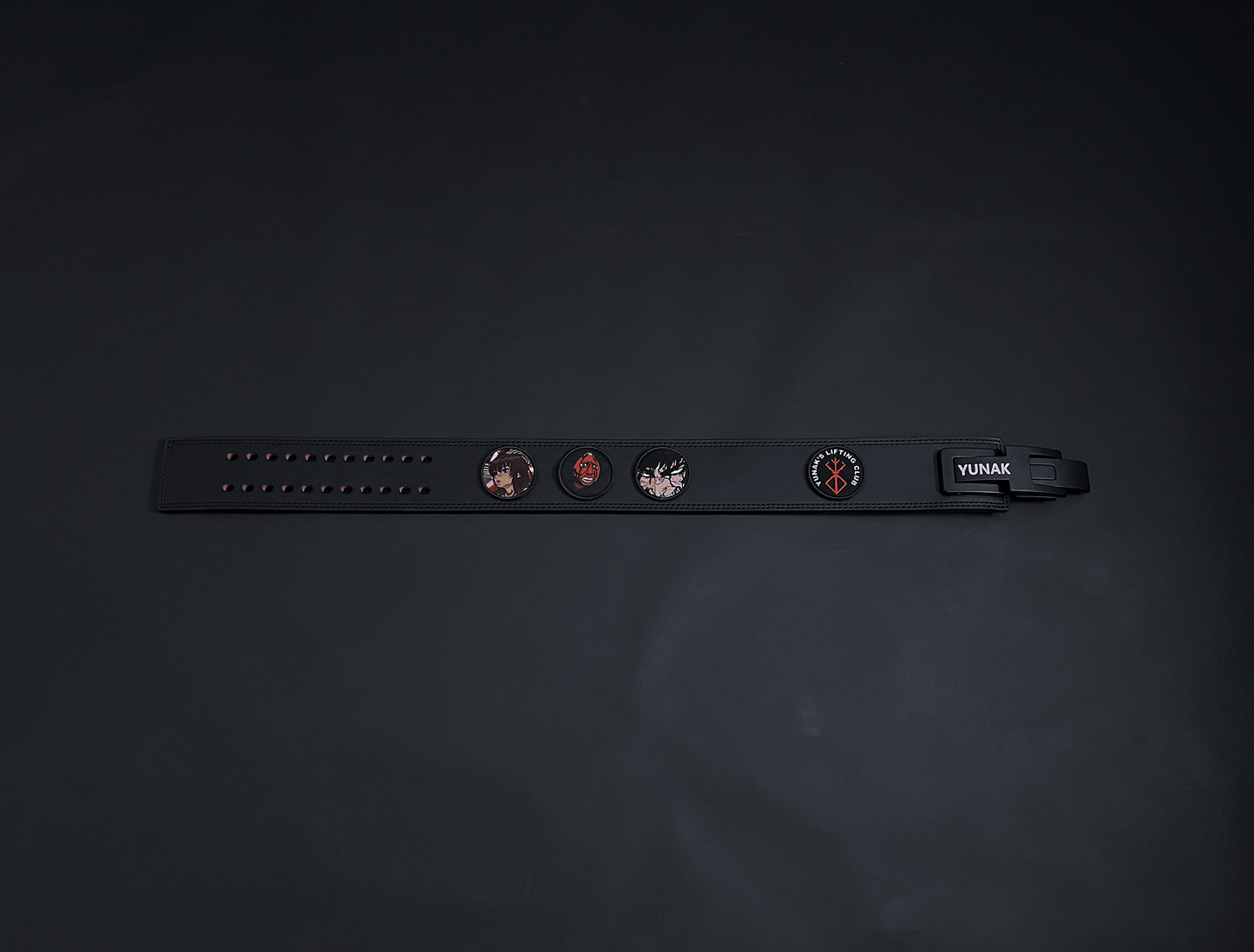 An anime powerlifting belt, 13mm thick and 4 inch wide. Featuring 4 embroidery patches inspired by Berserk. First patch is Casca, second is behelit, third is featuring Guts and the fourth is a Yunak's Lifting Club patch. The photo is top down view of the belt.