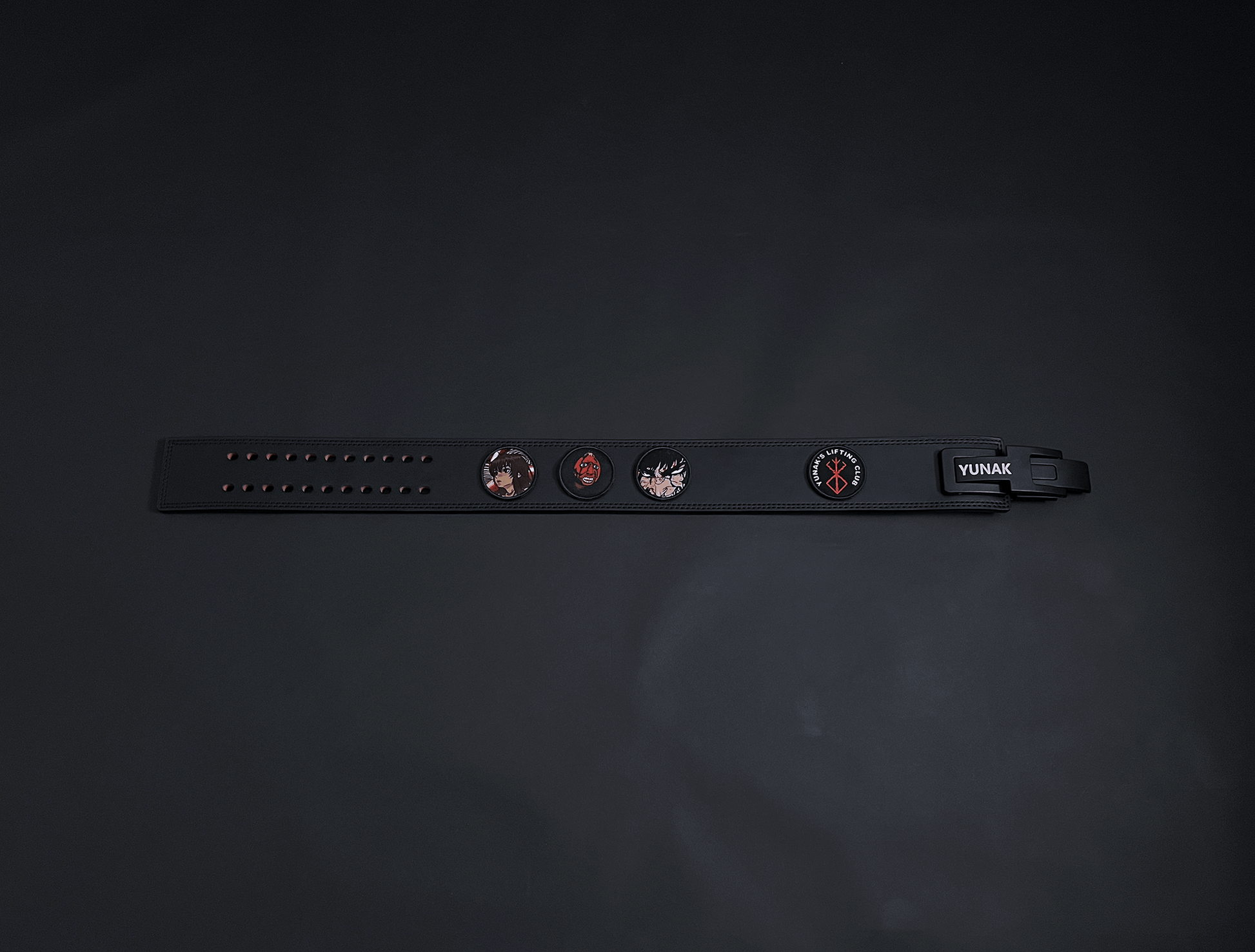 An anime powerlifting belt, 13mm thick and 4 inch wide. Featuring 4 embroidery patches inspired by Berserk. First patch is Casca, second is behelit, third is featuring Guts and the fourth is a Yunak's Lifting Club patch. The photo is top down view of the belt.