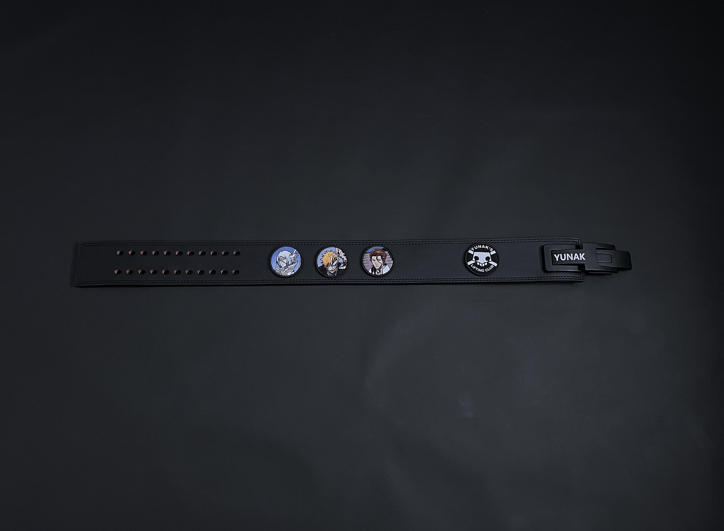 An anime powerlifting belt, 13mm thick and 4 inch wide. Featuring 4 embroidery patches inspired by Bleach. First patch is Rukia, second is Ichigo, third is featuring Aizen and the fourth is a Yunak's Lifting Club patch. The photo is top down view of the belt.