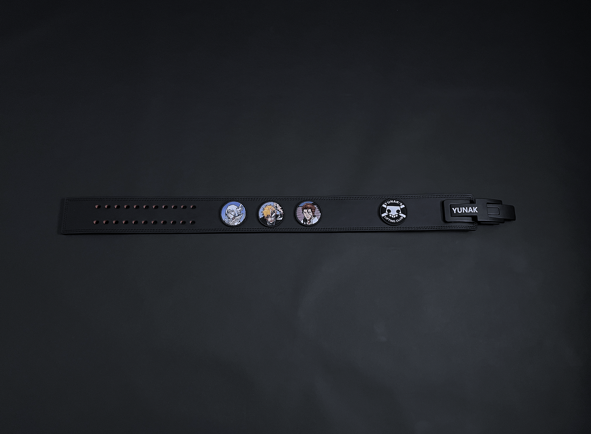 An anime powerlifting belt, 13mm thick and 4 inch wide. Featuring 4 embroidery patches inspired by Bleach. First patch is Rukia, second is Ichigo, third is featuring Aizen and the fourth is a Yunak's Lifting Club patch. The photo is top down view of the belt.