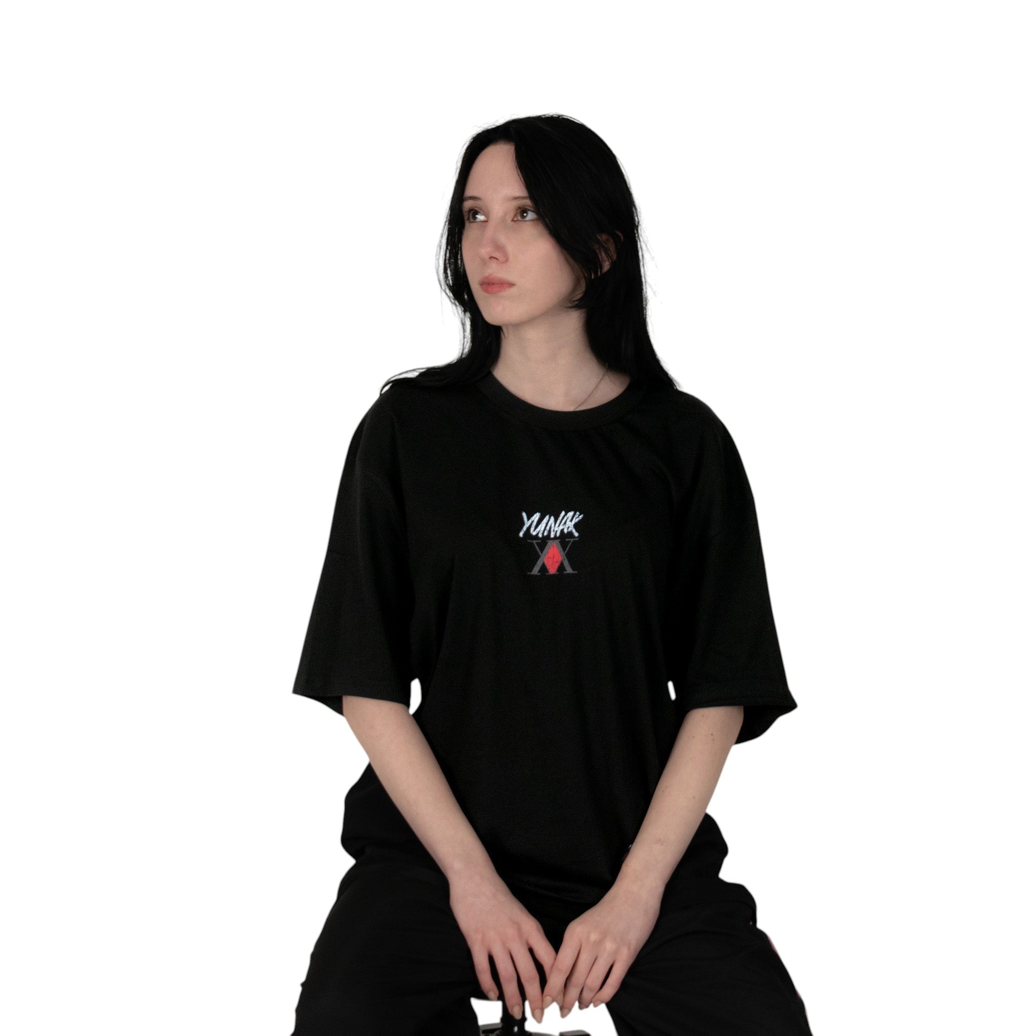 Person wearing a black t-shirt with Yunak x HunterxHunter graphic on the front, sitting against a white background