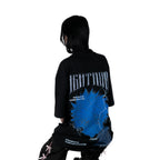 Person wearing a black t-shirt with graphic design of Killua from HunterxHunter on the back, sitting against a white background